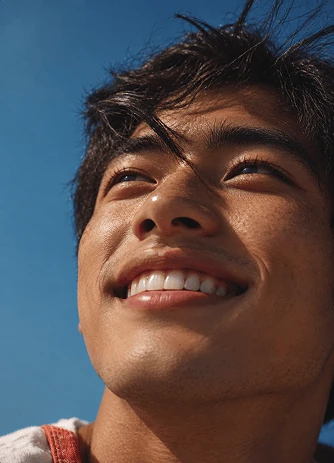 Close-up of a smiling young man looking up against a clear blue sky